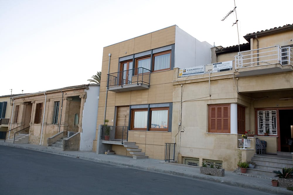 Το κτιριακό μέτωπο από τα ΒΑ. Στην πρόσοψη, ένας αυστηρός κάνναβος ακολουθεί τις περασιές του γειτονικού κτιρίου στα βόρεια όσον αφορά την οριζόντια κατεύθυνση, ενώ στην κατακόρυφη ο κάνναβος συλλειτουργεί με τα κατακόρυφα γεωμετρικά στοιχεία της όψης (μεταλλικοί στύλοι, ανοίγματα, μπαλκόνι), τονίζοντας και συνεχίζοντας τη ρυθμική επανάληψη που συναντούμε και στα γειτονικά κτρίρια, © Χρήστος Τσεκούρας